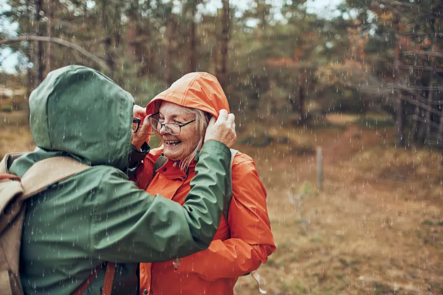 Twee vrouwen lopen door het bos het regent en lachen naar elkaar