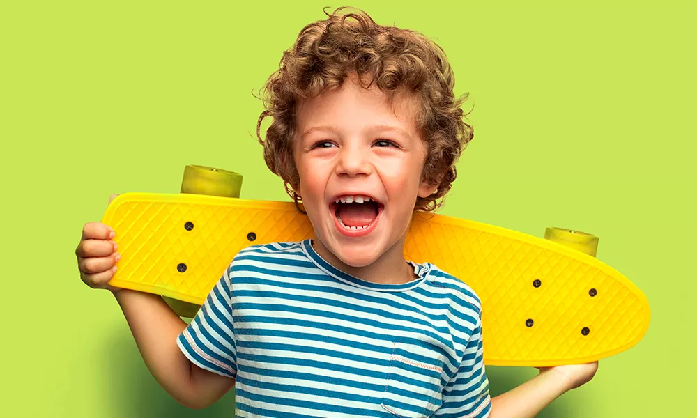 Kind met krulletjes, gestreept shirt en een geel skateboard